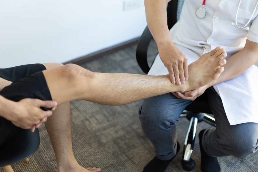 A medical professional examining a patient's leg during a consultation.